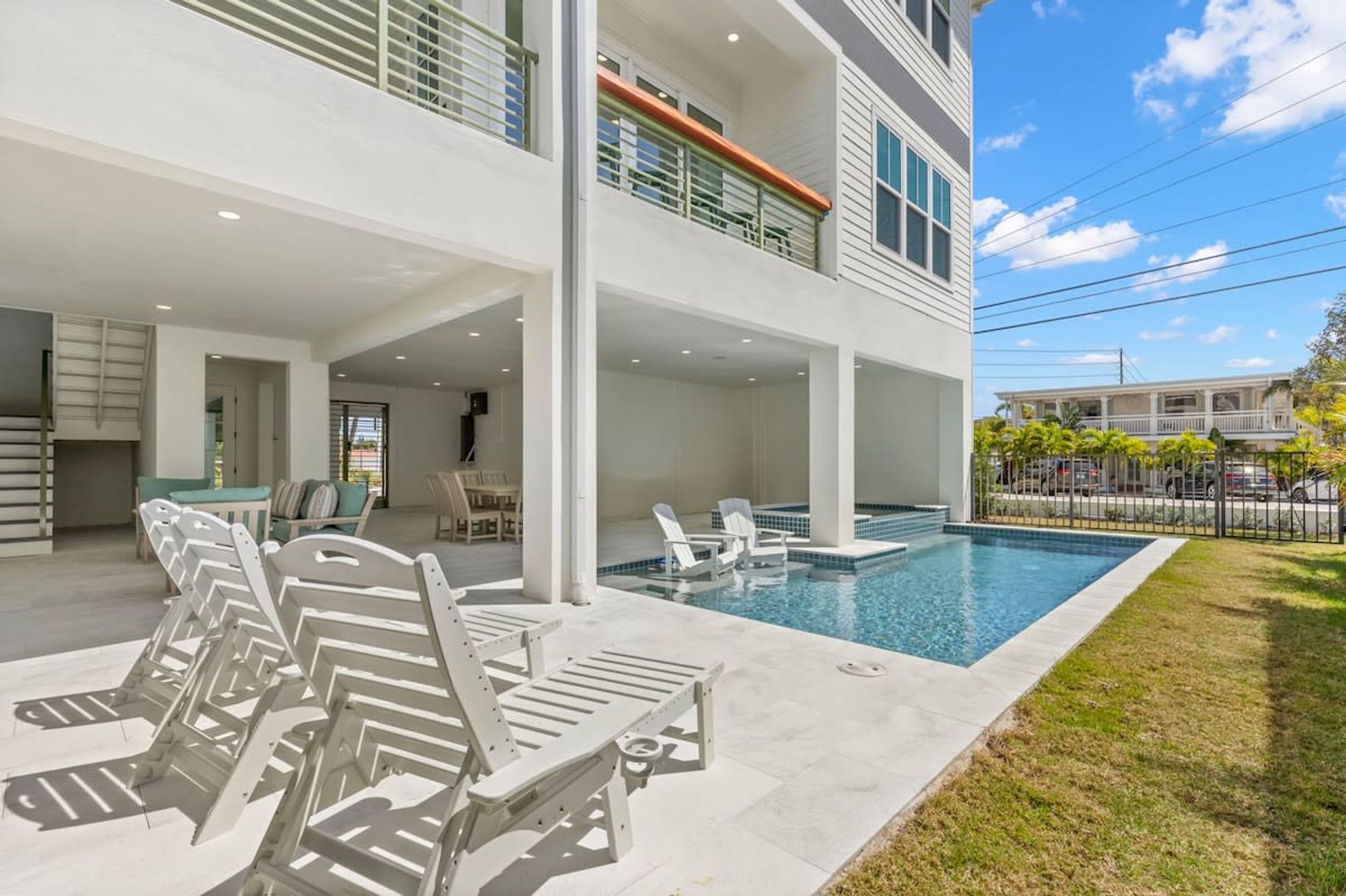 A modern two-story building with a swimming pool, outdoor seating, and a covered patio area.