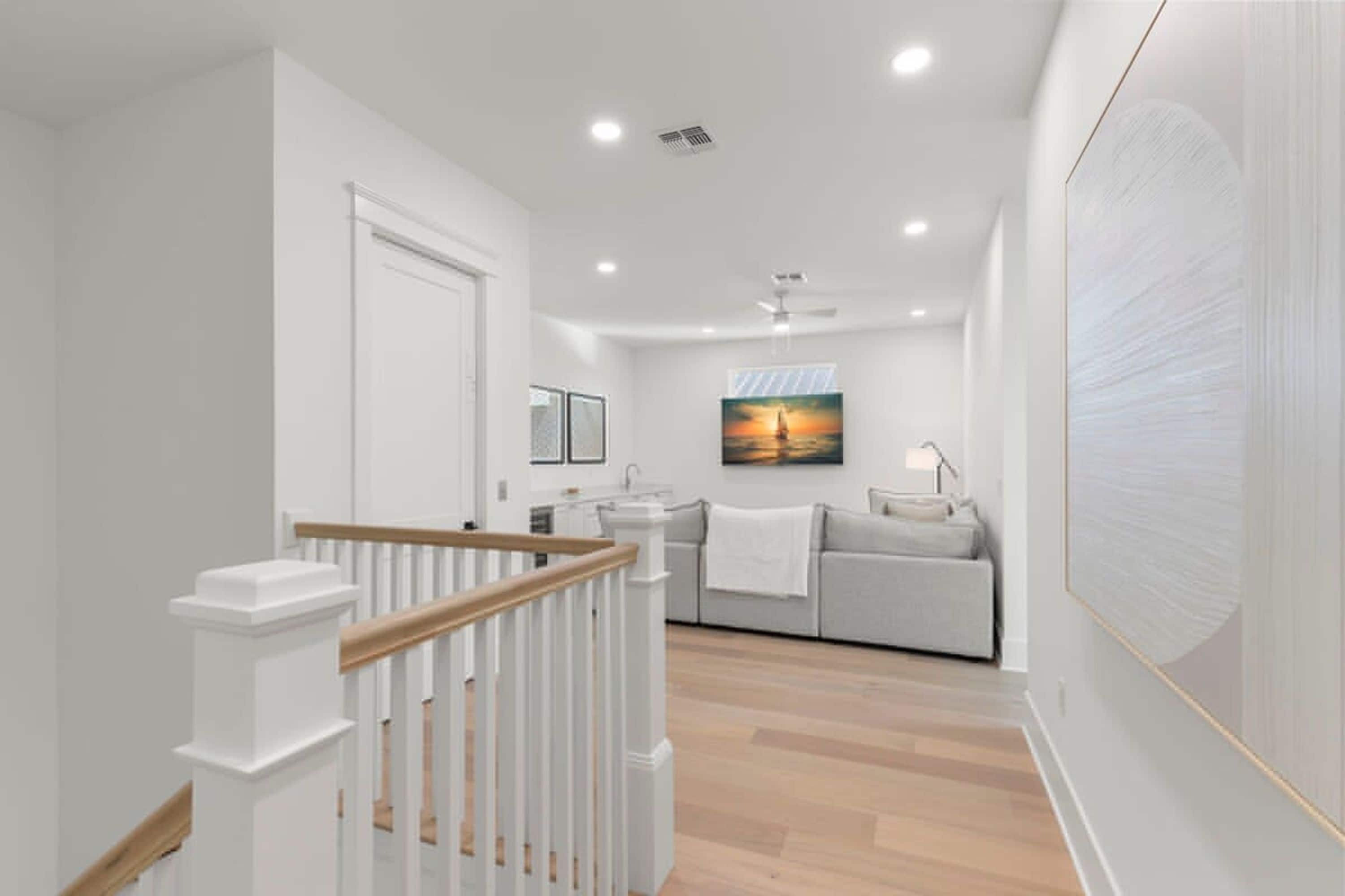 A modern interior with a staircase, a kitchen area, and a living space with a painting.