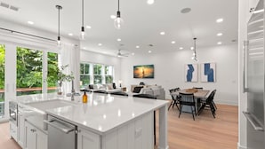 A modern kitchen with a large island, white cabinetry, and pendant lighting.