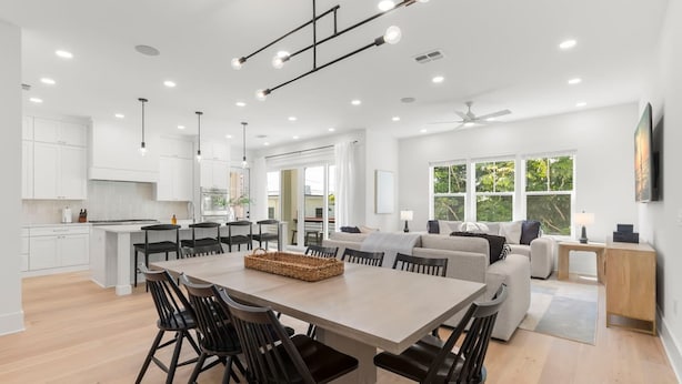 A spacious kitchen with a central island, modern pendant lights, and a dining area with a large table and chairs.