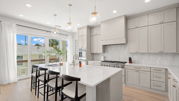 Una cocina moderna con una isla grande, taburetes de bar e iluminación colgante.