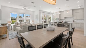 Una cocina amplia con armarios blancos, una mesa de comedor de madera y un ventilador de techo.