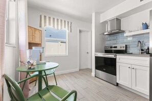 A compact kitchen with a stove, oven, and white cabinets. - Studio w/ King Bed Heated Pool, Steps to Beach! (Clearwater Beach)