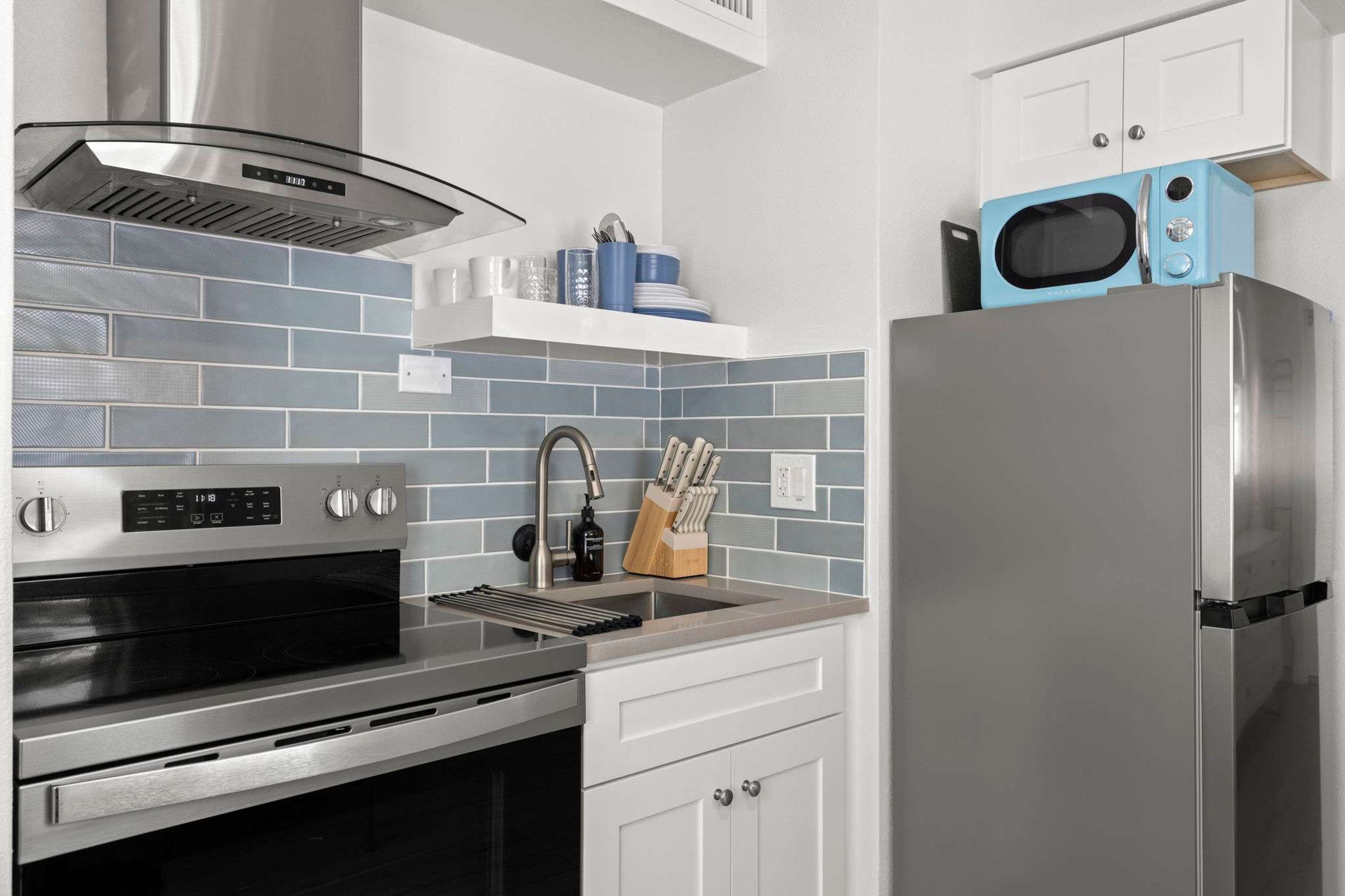 Una cocina moderna con electrodomésticos de acero inoxidable, un microondas y un bloque para cuchillos.