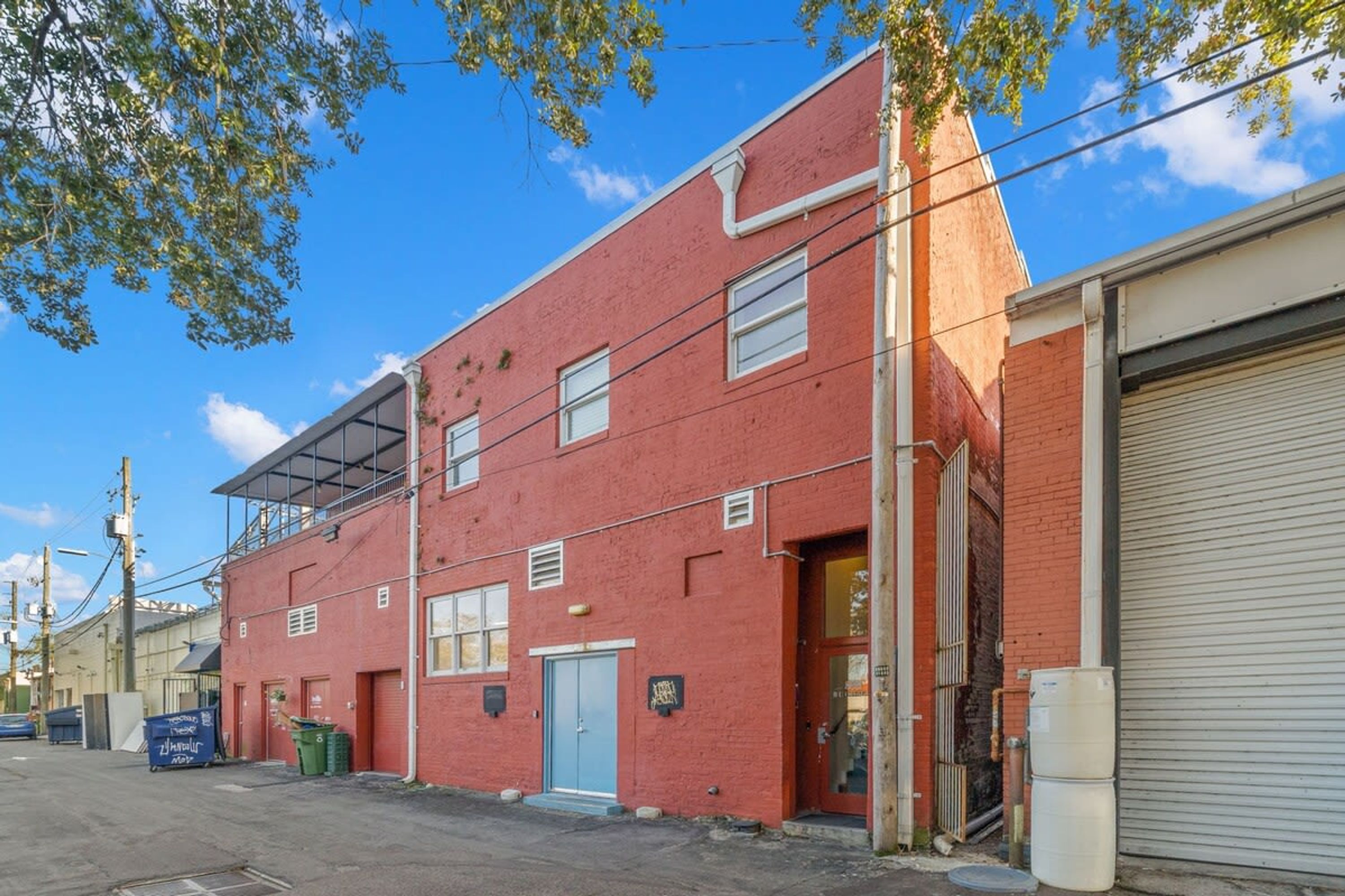 Een gebouw van rode baksteen met een gesloten garage, een blauwe deur en een klein bord aan de muur.