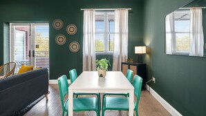 A dining area with a white table and green chairs, a potted plant, and decorative wall plates. - NEW Rumba Roost Upscale Ybor Studio On 7th Ave (Tampa)