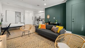 A modern living room with a sofa, chairs, a dining table, and a kitchen in the background.