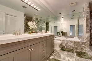 Une salle de bain moderne avec un meuble-lavabo en marbre, un grand miroir et une baignoire.