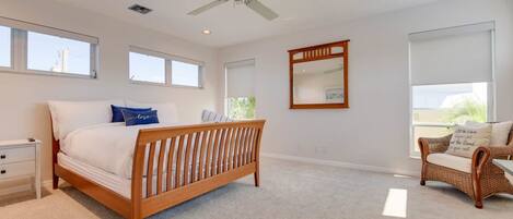 A bedroom with a wooden bed, a nightstand, a wicker chair, and a ceiling fan.