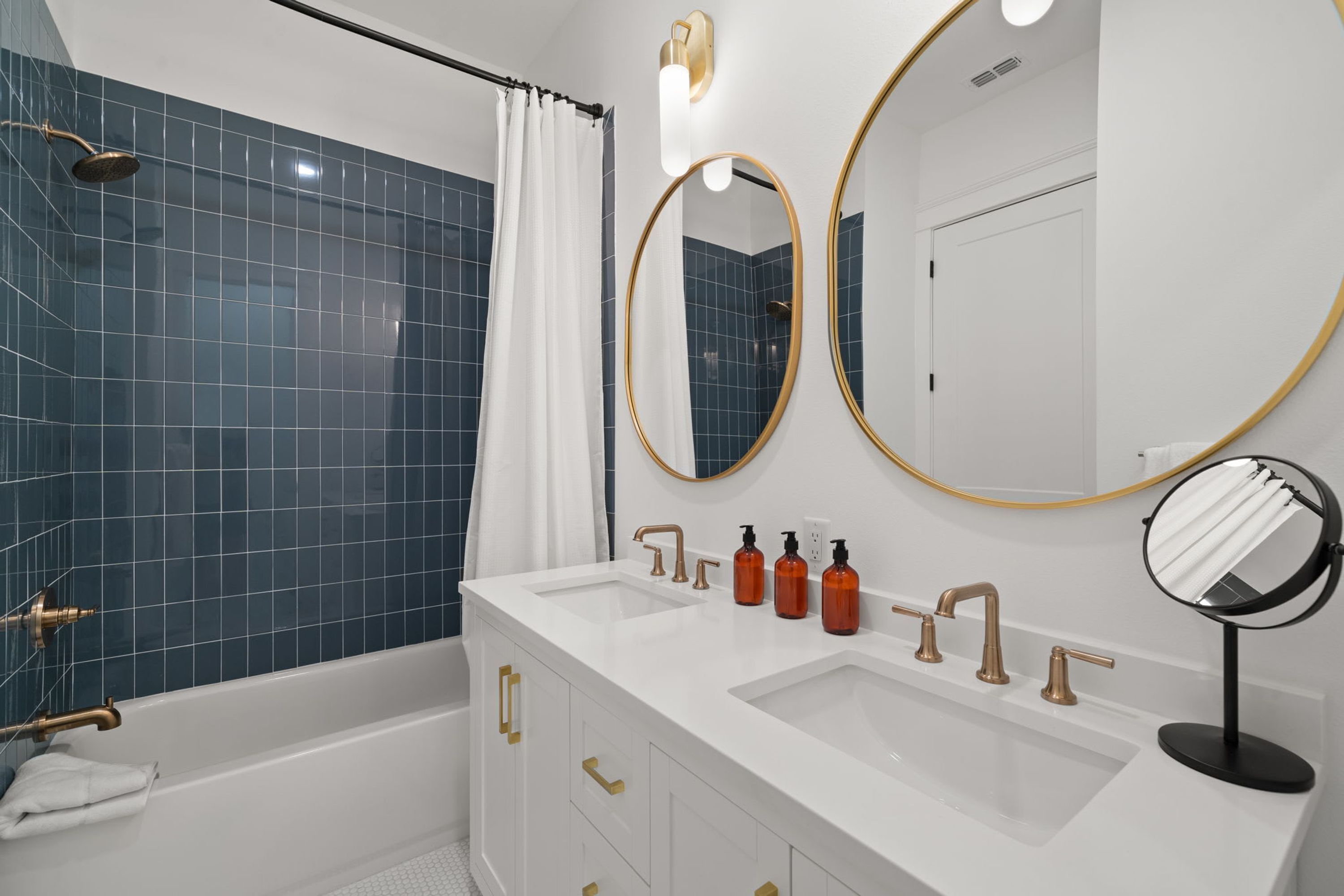 A modern bathroom with a bathtub, two sinks, and a shower.