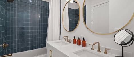 A modern bathroom with a bathtub, two sinks, and a shower.