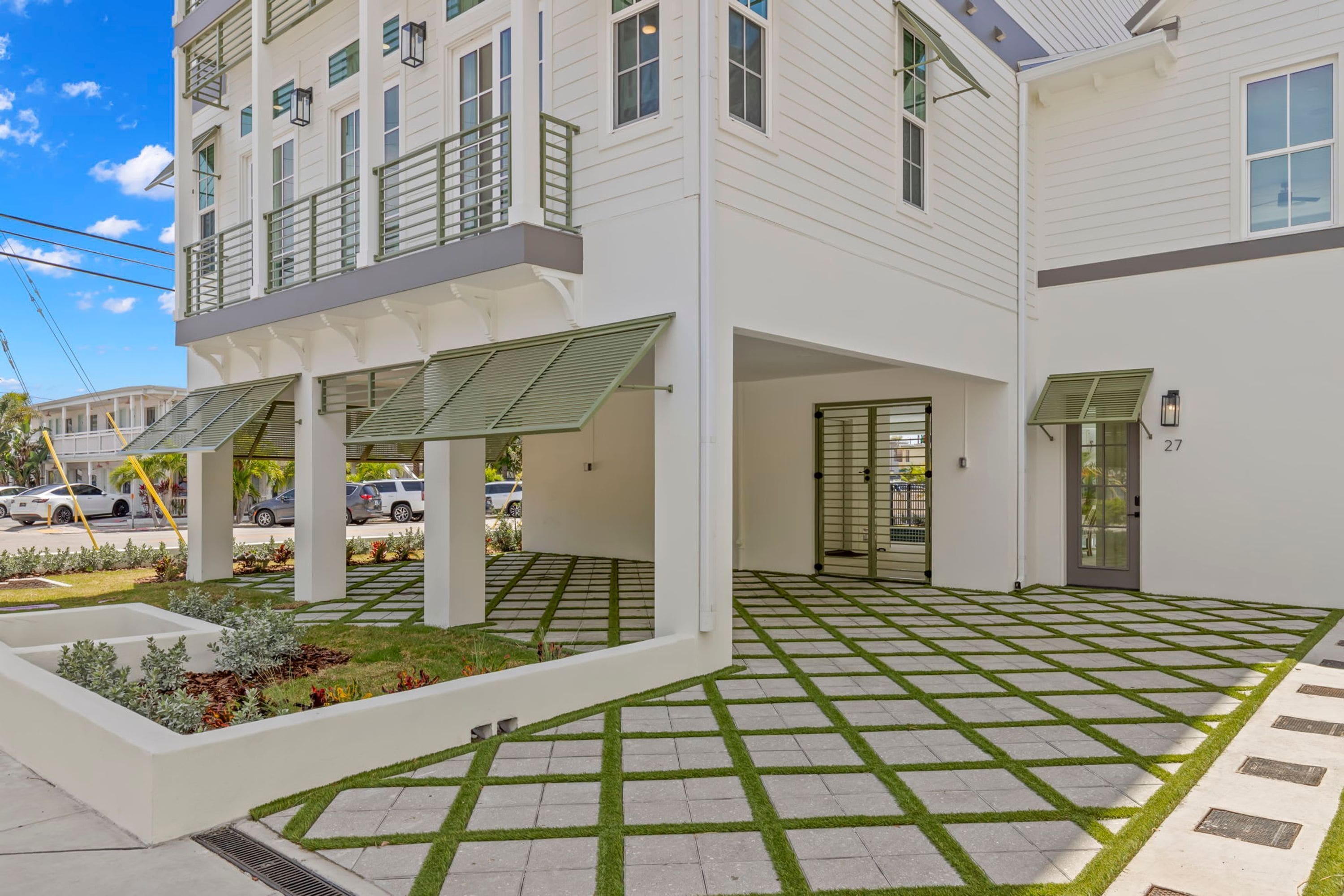 A modern building with a covered outdoor area, a gated entrance, and a paved driveway.