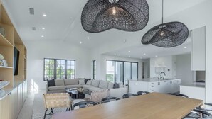 A modern living space with a large wooden dining table, a sofa set, and a kitchen area. - Brand New Catchlight House With Private Pool (Key West)