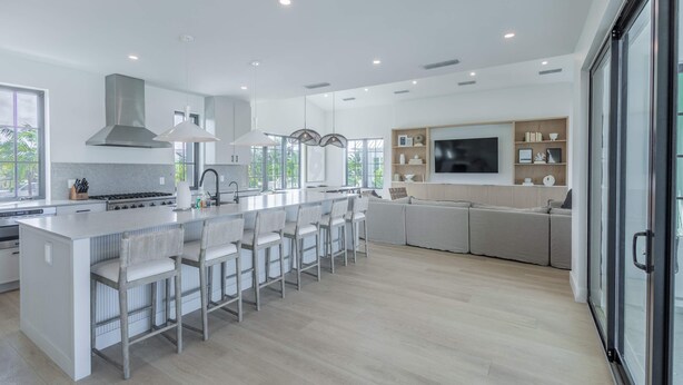 A modern kitchen with a central island, bar stools, and a large window. - Brand New Catchlight House With Private Pool (Key West)