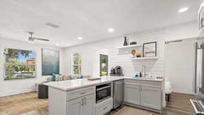 A modern kitchen with white cabinetry, a large island, and a built-in oven. - NEW Soho Oasis - Stunning Home In Heart of Soho (Tampa)