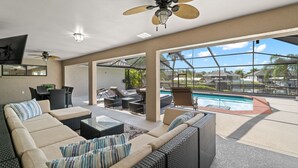A spacious outdoor living area with a pool, comfortable seating, and a ceiling fan. - NEW Surfside Beach House Heated Pool Boat Dock (Apollo Beach)
