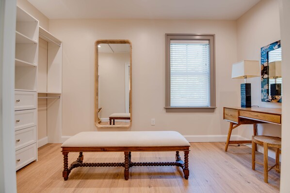 Une chambre à coucher avec un banc en bois, une armoire, un bureau et un miroir.