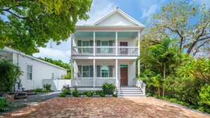A two-story house with a front porch, a brick driveway, and lush greenery around. - NEW The Rigby House - Pvt Pool Amazing Location (Key West)