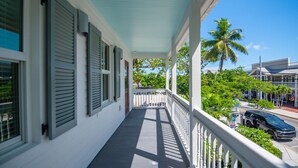 A covered porch with a view of a street and palm trees. - NEW The Rigby House - Pvt Pool Amazing Location (Key West)
