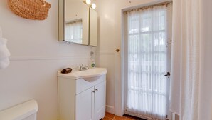 Ein Badezimmer mit Waschbecken, Spiegel und einem Korbwägelchen an der Wand.