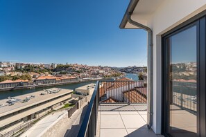Een balkon met uitzicht op een rivier, gebouwen en een brug.