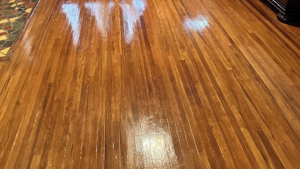 A living room with a brown leather sofa, a patterned rug, and a wooden floor. - Charming 3-bedroom house with AC and WiFi in welcoming Mobile (Mobile)