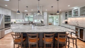 A modern kitchen with a large island, bar stools, pendant lights, and stainless steel appliances. - Living the Dream- Lakefront-Dock (Hiawassee)