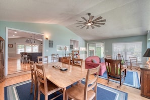 Un vaste espace de vie comprenant une table à manger en bois, des chaises, un canapé rouge et un ventilateur de plafond.