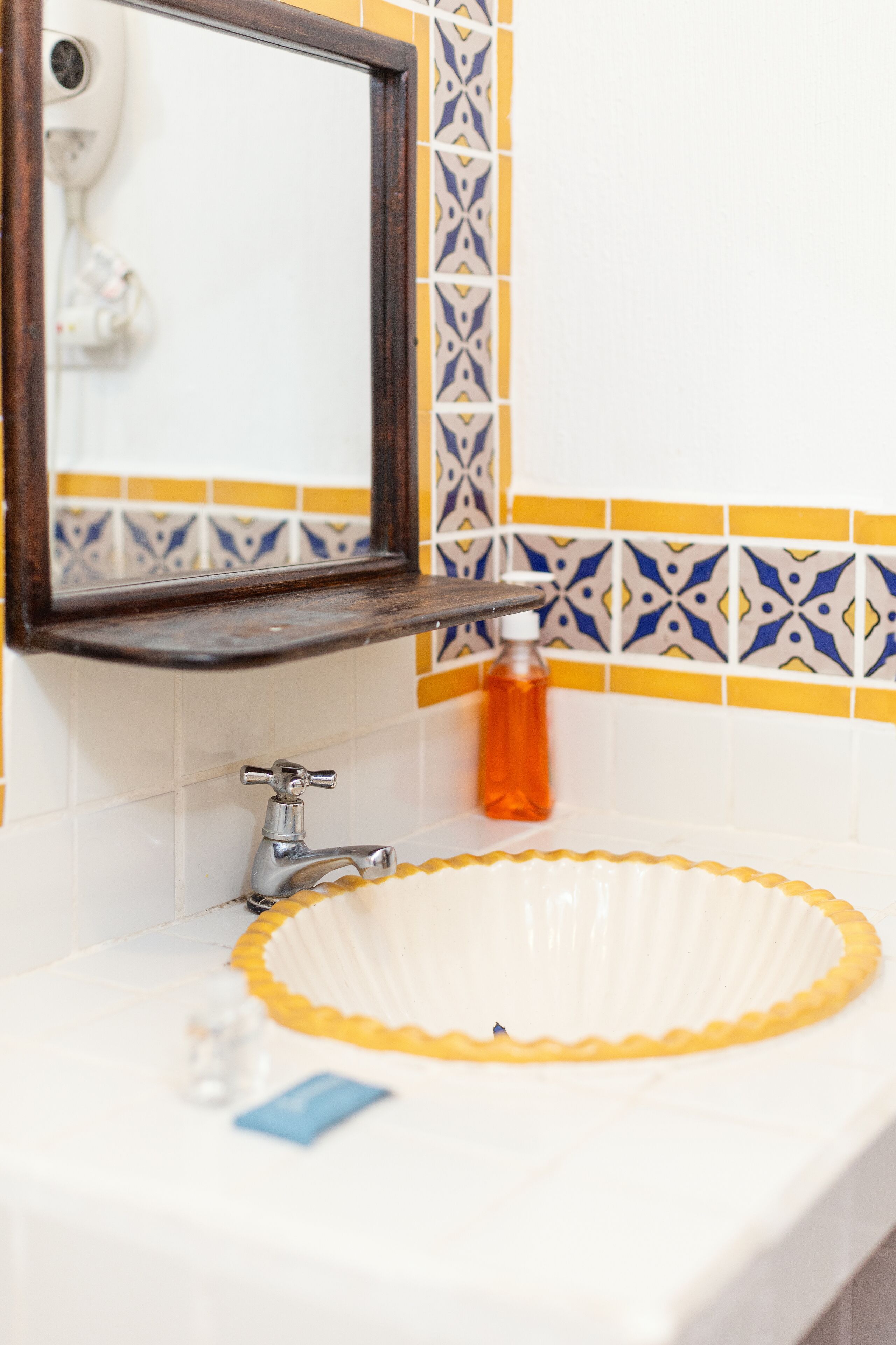 A bathroom with a white sink, a mirror, and a patterned tile backsplash.