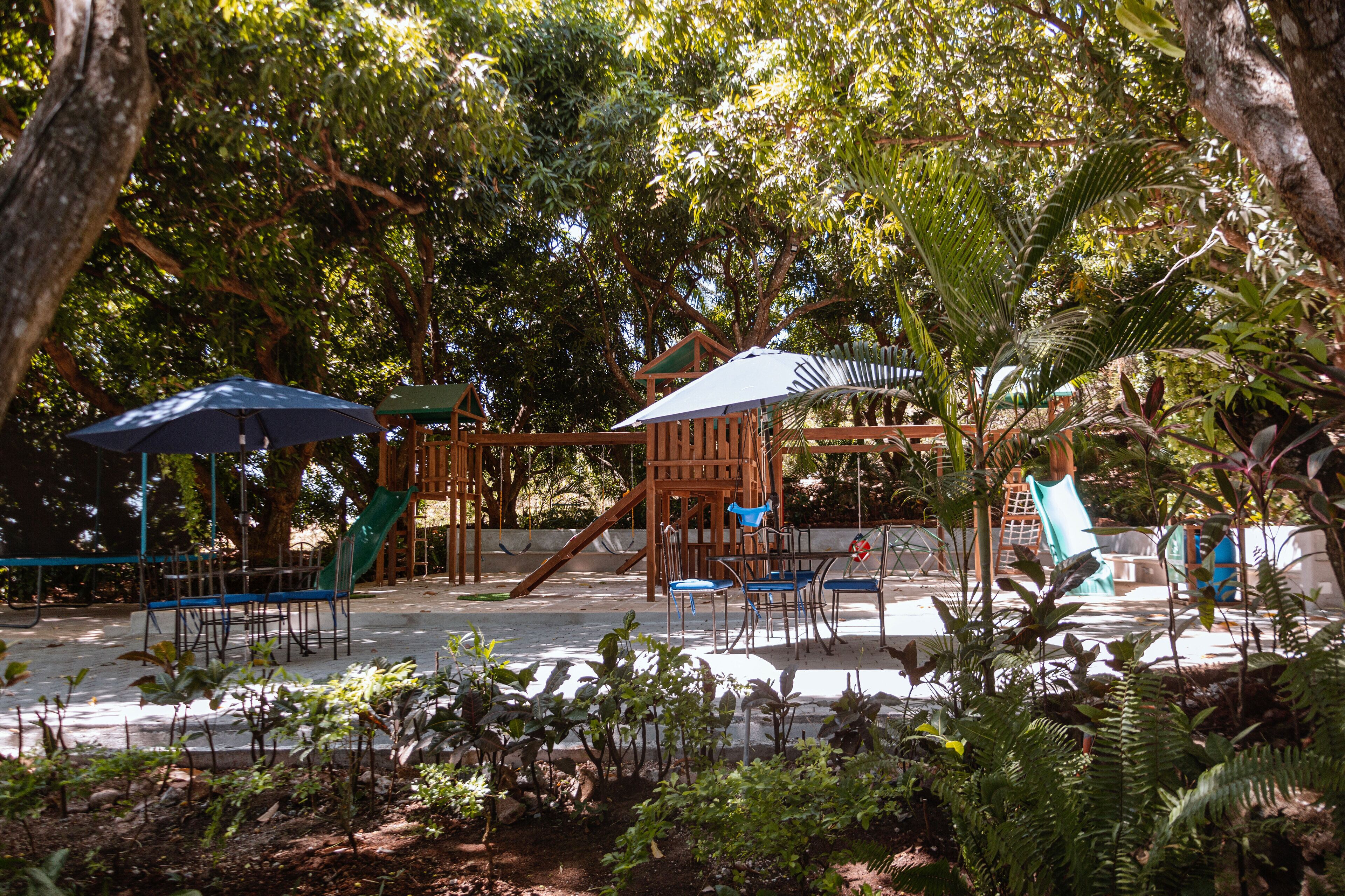 Un parque infantil con toboganes y estructuras para escalar, rodeado de árboles.