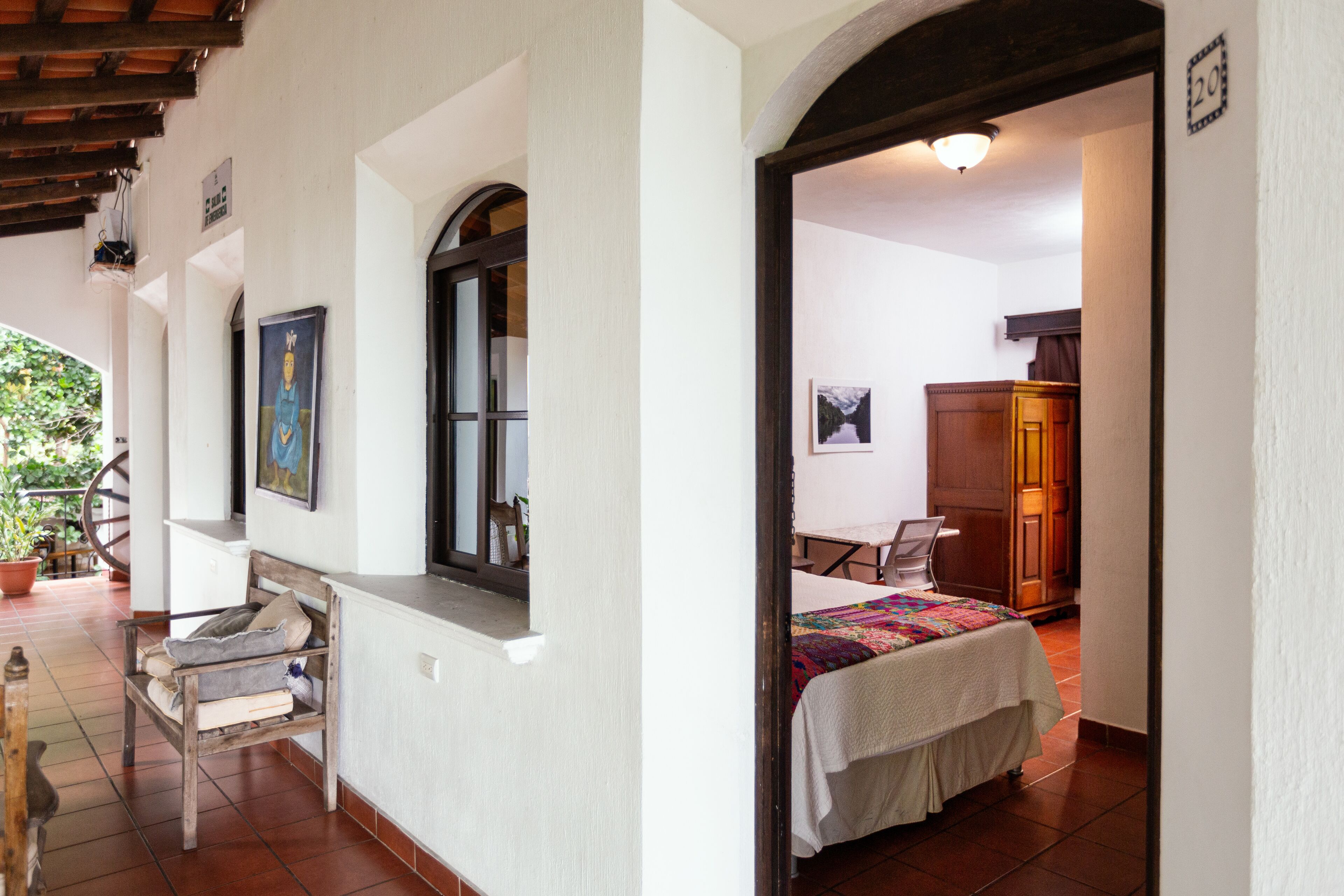 Una stanza con un letto, una scrivania e una sedia. Si vede una finestra e una porta.