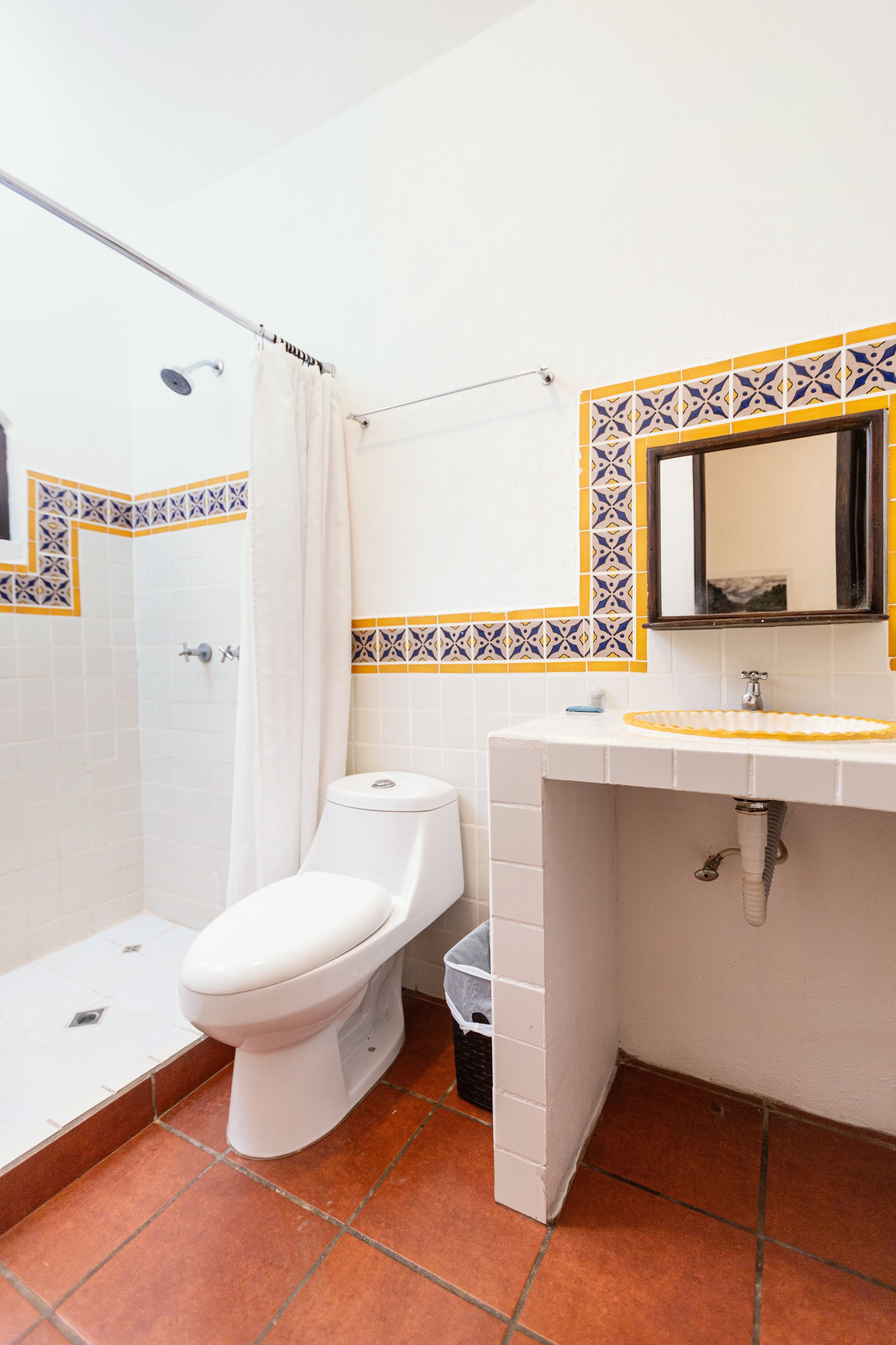 A bathroom with a white toilet, a shower, and a sink with a mirror above it.