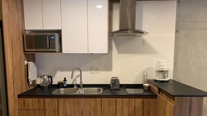 Een moderne keuken met houten kastjes, een roestvrijstalen spoelbak, een magnetron, een broodrooster en een koffiezetapparaat.