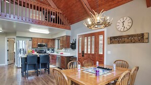 A spacious kitchen with wooden cabinets, a dining area with a wooden table and chairs, and a lofted seating area with a wooden railing.