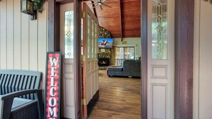 A wooden exterior with a 'WELCOME' sign, a fireplace, and a television in the background.