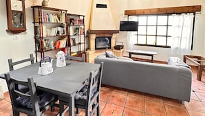 Una sala de estar acogedora con una mesa de comedor, estanterías, una chimenea y un televisor.