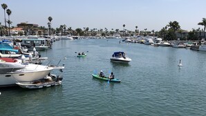 A marina with various boats docked, including a green kayak and a motorboat. - Steps from the sand, well-stocked, clean, family beach home. AC & easy pkg. (Long Beach)