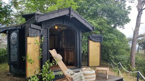 Een eenvoudige houten blokhut met een veranda, een bankje en een kleine tafel met een dienblad.