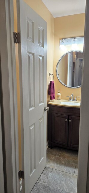 Bathroom features a round mirror, a vanity, and a bathtub.