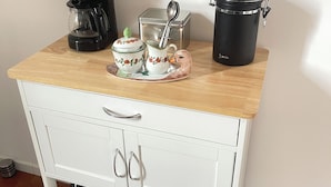 Eine Küchenarbeitsplatte mit Kaffeemaschine, Teekanne, Zuckerlöffel und Thermoskanne.