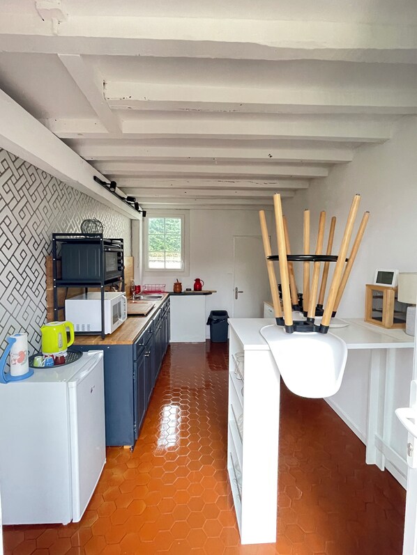 Une cuisine compacte dotée d’un îlot central, de meubles blancs et d’un dosseret orné d’un motif en chevrons.