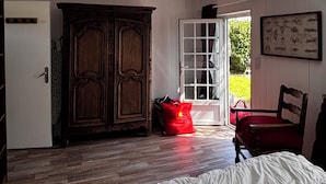 Ein Zimmer mit einem Bett, einem Holzschrank und einer Tür, die nach draußen führt.