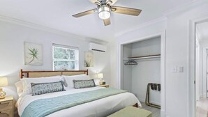 A bedroom with a bed, bedside tables, a ceiling fan, a window, and a closet. - Battery Place (Savannah)