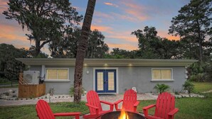 A house with a blue door, a fire pit, and red Adirondack chairs. - Battery Place (Savannah)