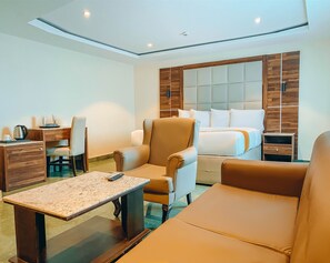 A modern hotel room with a bed, a desk, a chair, a sofa, and a small table. - WestPoint Hotels Limited (Abuja)