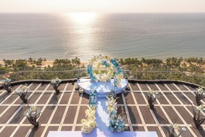 Relax on the rooftop terrace with a serene ocean view, surrounded by a beautiful floral arrangement and stylish glass tables.