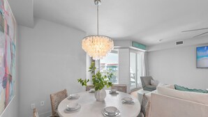 Een eetgedeelte met een ronde tafel, witte stoelen en een hanglamp.