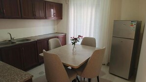 Cuina amb taula de menjador, cadires, nevera i rentaplat.