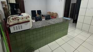 A kitchen with a tiled backsplash, a coffee maker, and a dining area with chairs. - Apartamento Privê do Atlântico Salinas (Salinópolis)