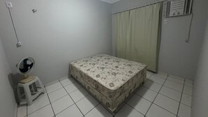 A room with a bed, a standing fan, a heater, and a window with curtains. - Apartamento Privê do Atlântico Salinas (Salinópolis)